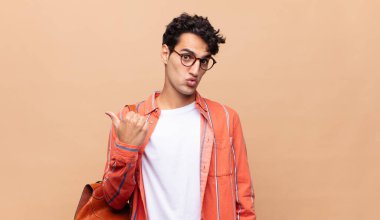 Genç öğrenci inançsızlıktan şaşkın şaşkın bakıyor, yan taraftaki objeyi işaret ediyor ve 