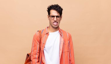 Genç bir öğrenci tiksinmiş ve rahatsız olmuş hissediyor. Dilini dışarı çıkarıyor. Çirkin ve iğrenç bir şeyden hoşlanmıyor.