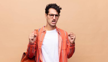 Genç öğrenci öfkeli bir ifadeyle ya da yumruklarıyla başarıyı kutlarken agresif bir şekilde bağırıyor.