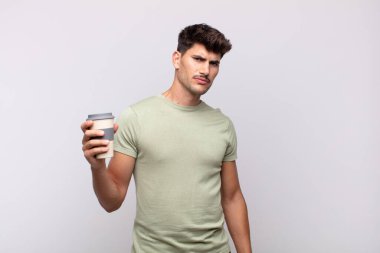 Kahveli genç adam üzgün, üzgün ya da kızgın ve olumsuz bir tavır takınıyor, anlaşmazlıkla kaşlarını çatıyor.