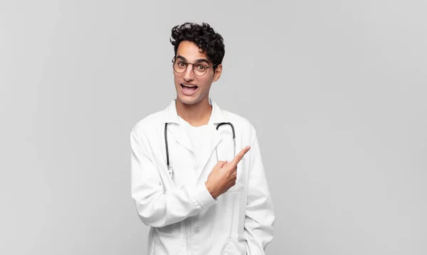 Ung Läkare Ser Upphetsad Och Förvånad Pekar Sidan Och Uppåt — Stockfoto