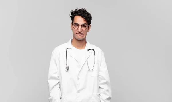 Młody Lekarz Wyglądający Zdziwionego Zdezorientowanego Gryzący Wargę Nerwowym Gestem Nie — Zdjęcie stockowe