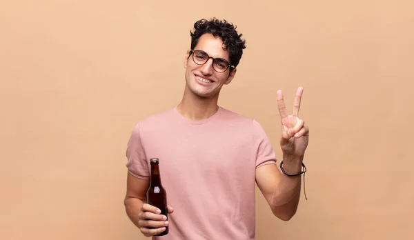 Молодий Чоловік Пивом Посміхається Виглядає Щасливим Безтурботним Позитивним Жестикулюючи Перемогу — стокове фото