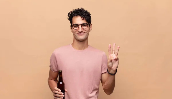 Jovem Com Uma Cerveja Sorrindo Parecendo Amigável Mostrando Número Dois — Fotografia de Stock