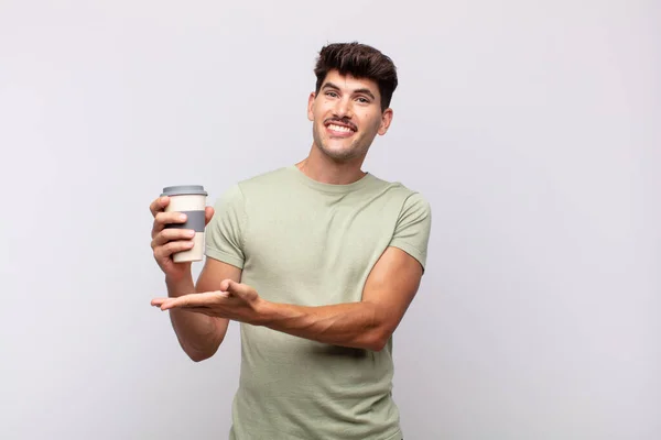 Joven Con Café Sonriendo Alegremente Sintiéndose Feliz Mostrando Concepto Espacio —  Fotos de Stock