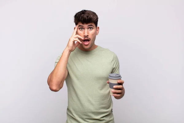 Ung Man Med Kaffe Ser Förvånad Öppen Mun Chockad Förverkliga — Stockfoto