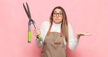 Genç sarışın kadın şaşkın ve şaşkın hissediyor, şüpheci, farklı seçenekleri tartıyor veya komik bir ifadeyle seçiyor.