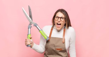 Genç sarışın kadın agresif bir şekilde bağırıyor, çok kızgın, sinirli, öfkeli ya da sinirli görünüyor.