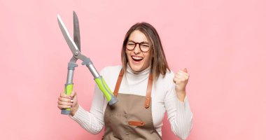 Genç sarışın kadın öfkeli bir ifadeyle bağırıyor ya da yumruklarıyla başarıyı kutluyor.