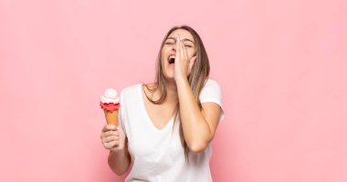 Genç sarışın kadın mutlu, heyecanlı ve pozitif hissediyor. Elleri ağızda, bağırarak bağırıyor.