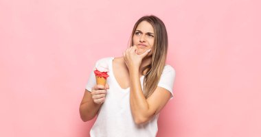 Genç sarışın kadın düşünüyor, kuşkulu ve şaşkın hissediyor, farklı seçeneklerle, hangi kararı vereceğini merak ediyor.