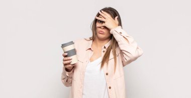 Genç sarışın kadın şok olmuş, korkmuş ya da korkmuş görünüyordu. Yüzü elle kaplıydı ve parmaklarının arasından bakıyordu.