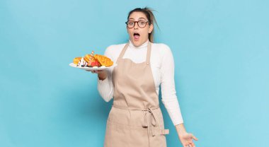 Genç sarışın kadın şok olmuş ya da şaşırmış görünüyor, ağzı açık bir şekilde 