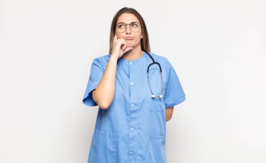 Genç sarışın kadın düşünüyor, kuşkulu ve şaşkın hissediyor, farklı seçeneklerle, hangi kararı vereceğini merak ediyor.