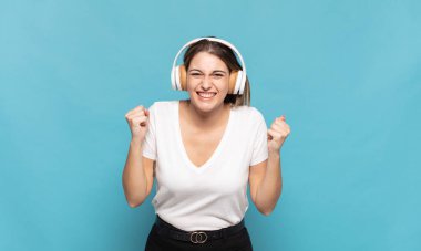 Genç sarışın kadın öfkeli bir ifadeyle bağırıyor ya da yumruklarıyla başarıyı kutluyor.