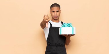 Genç siyahi adam kızgın, sinirli, hayal kırıklığına uğramış ya da canı sıkkın, ciddi bir bakışla başparmağını kaldırıyor.