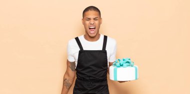 Genç siyah adam agresif bir şekilde bağırıyor, çok kızgın, sinirli, öfkeli ya da sinirli görünüyor, hayır