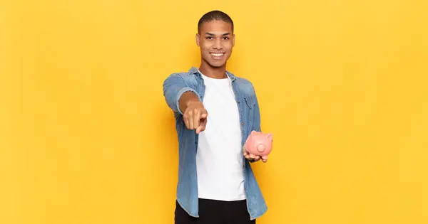 young black man pointing at camera with a satisfied, confident, friendly smile, choosing you