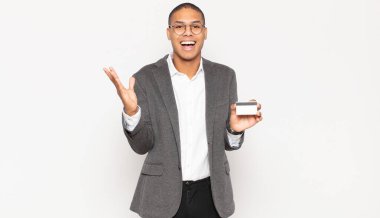 Genç siyah adam mutlu, şaşırmış ve neşeli hissediyor, pozitif bir tavırla gülümsüyor, bir çözüm ya da fikir buluyor.