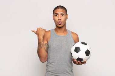 Genç siyahi adam inançsızlıktan şaşkın şaşkın bakıyor, yan taraftaki objeyi işaret ediyor ve diyor ki: