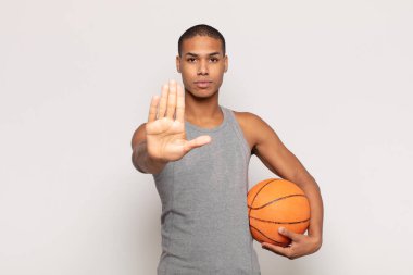 Genç siyahi adam ciddi, sert, hoşnutsuz ve kızgın görünüyor.