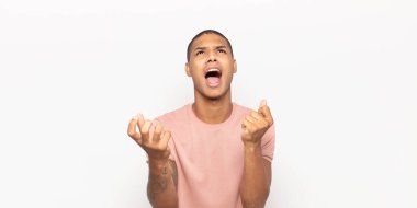 Genç siyah adam umutsuz ve sinirli görünüyor, stresli, mutsuz ve sinirli, bağırıyor ve çığlık atıyor.