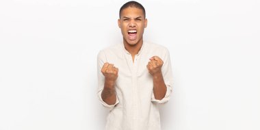 Genç siyahi adam sinirli, sinirli, sinirli bakışlar ve sıkı yumruklar ile agresif bir şekilde bağırıyor.