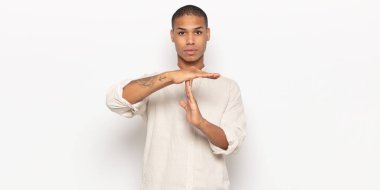 Genç siyahi adam ciddi, sert, kızgın ve canı sıkkın görünüyor.