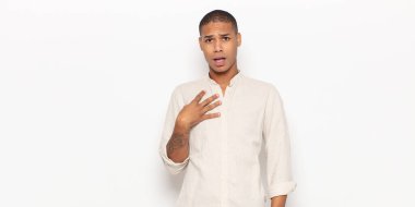 Genç siyah adam şaşkın, şaşkın ve şaşırmış hissediyor, elleri göğsünde ve ağzı açık, kim olduğunu söylüyor, ben?