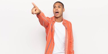 Genç siyahi adam şaşkın ve şaşırmış hissediyor, hayranlıkla yukarı bakıyor, şaşkın, ağzı açık bakıyor.