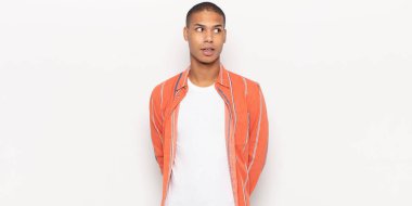 Genç siyah adam şok olmuş, mutlu, şaşkın ve şaşırmış hissediyor, ağzı açık bir şekilde yana bakıyor.