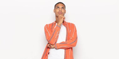 Genç siyah adam düşünceli, meraklı ya da hayal kuruyor, hayal kuruyor ve uzayı kopyalamak için yukarı bakıyor.