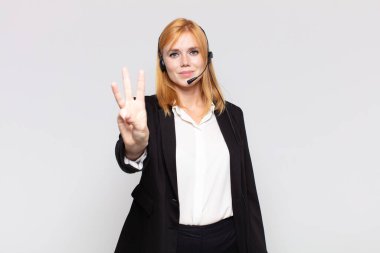 Güzel bir kadın gülümsüyor ve arkadaş canlısı görünüyor. Üç ya da üç numarayı gösteriyor. Elleri önde, geri sayıyor.