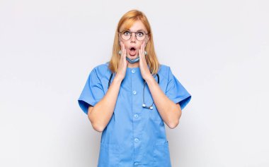 Güzel kadın şok olmuş ve korkmuş hissediyor, ağzı açık ve elleri yanaklarında korkmuş görünüyor.