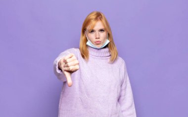 Güzel bir kadın sinirli, sinirli, sinirli, hayal kırıklığına uğramış ya da hoşnutsuz, ciddi bir bakışla başparmaklarını göstermiyor.