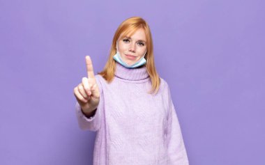 Güzel bir kadın gülümsüyor ve arkadaş canlısı görünüyor. Bir numarayı gösteriyor ya da ilk eli önde, geri sayıyor.