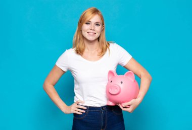 Güzel bir kadın mutlu bir şekilde gülümsüyor, eli kalçasında ve kendinden emin, olumlu, gururlu ve arkadaş canlısı bir tavırla.