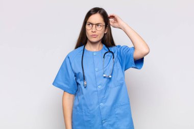 Güzel kadın şaşkın ve kafası karışmış hissediyor, başını kaşıyor ve yan tarafa bakıyor.