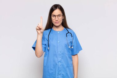 Güzel bir kadın gülümsüyor ve arkadaş canlısı görünüyor. Bir numarayı gösteriyor ya da ilk eli önde, geri sayıyor.