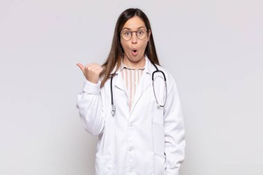 Güzel bir kadın inançsızlıktan şaşkın şaşkın bakıyor, yan taraftaki objeyi işaret ediyor ve diyor ki: