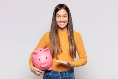 Güzel bir kadın neşeyle gülümsüyor, mutlu hissediyor ve bir konsepti fotokopi uzayında el ele vererek gösteriyor.