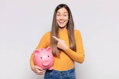 Güzel bir kadın heyecanlı ve şaşırmış görünüyor. Yana ve yukarı doğru uzayı gösteriyor.