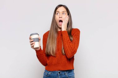 Güzel bir kadın mutlu, heyecanlı ve şaşırmış hissediyor, iki eli yüzü üzerinde yana bakıyor.