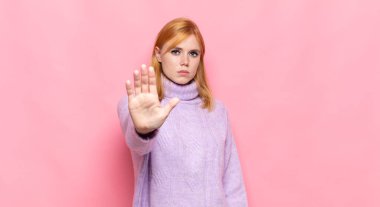 Kızıl saçlı güzel bir kadın ciddi, sert, hoşnutsuz ve kızgın görünüyor.