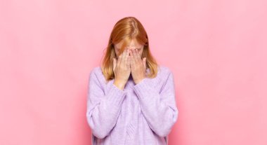 Kızıl saçlı güzel bir kadın üzgün, hayal kırıklığına uğramış, gergin ve depresif, iki eliyle yüzünü kaplayan, ağlayan