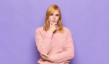 Kızıl saçlı güzel kadın ciddi görünüyor, kafası karışık, kararsız ve düşünceli, seçenekler ve seçenekler arasında şüpheci.