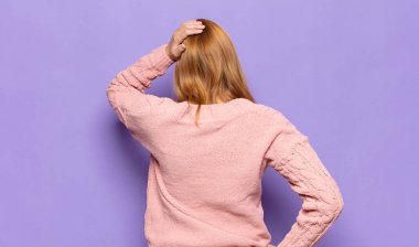 Kızıl saçlı güzel bir kadın bilgisiz ve kafası karışık, bir çözüm düşünüyor, eli kalçasında, diğeri kafasında, dikiz aynasından.