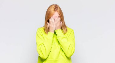 Kızıl saçlı güzel bir kadın üzgün, hayal kırıklığına uğramış, gergin ve depresif, iki eliyle yüzünü kaplayan, ağlayan