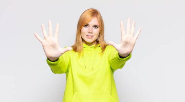 Kızıl saçlı güzel kadın gülümsüyor ve arkadaş canlısı görünüyor, onuncu ya da onuncu numarayı gösteriyor, eli önde, geriye doğru sayıyor.