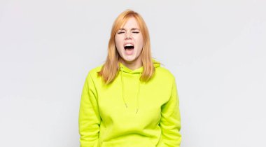 Kızıl saçlı, güzel bir kadın agresif bir şekilde bağırıyor, kızgın, sinirli, sinirli ya da sinirli görünüyor.